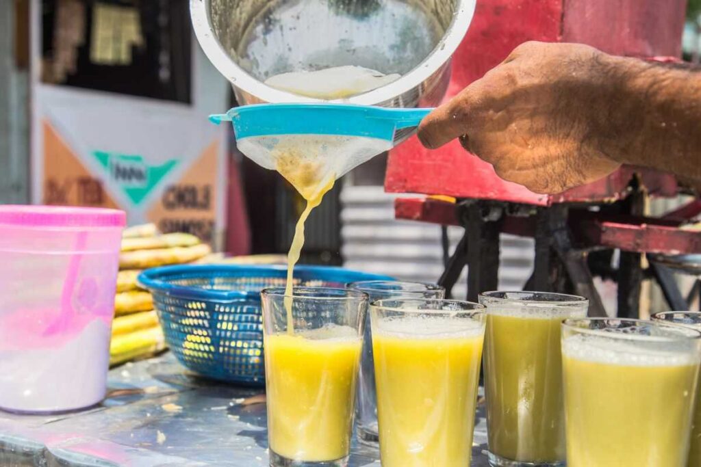 Homem preparando caldo de cana para vender com pastel. 