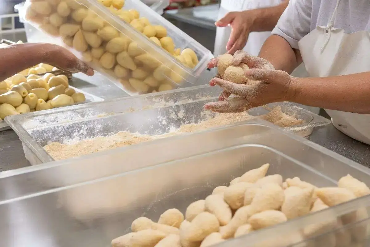 Homem preparando massa de coxinha congelada para vender,